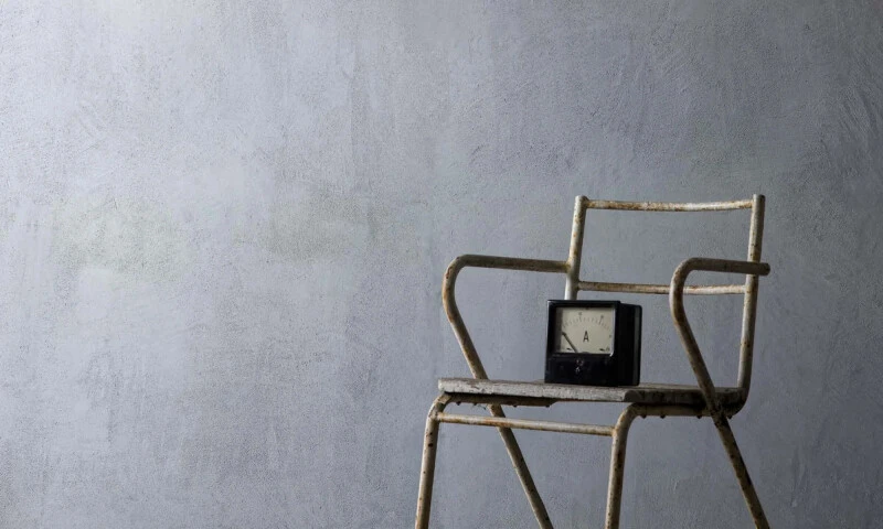 A grey Venetian Plaster wall with a rustic chair in front. 