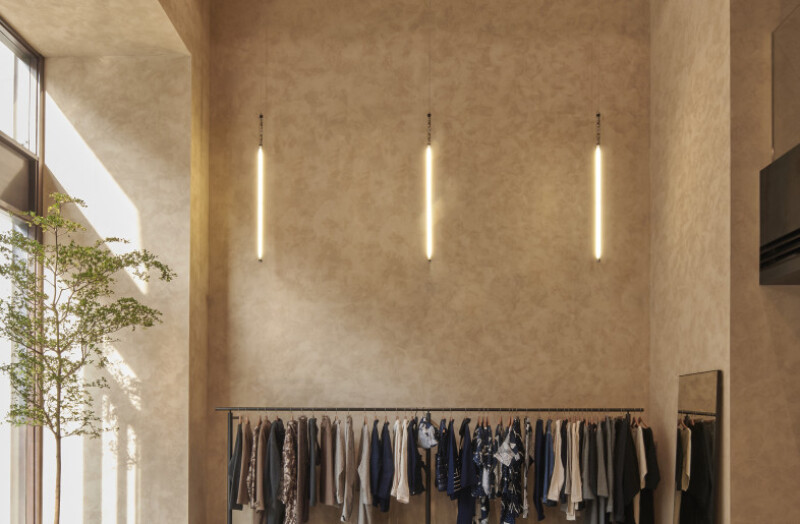nterior of a modern retail clothing store featuring softly textured Viero Ghibli wall finish in a warm, neutral tone. The high ceilings, vertical pend